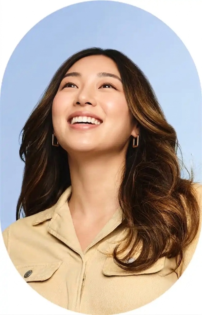 위를 바라보며 밝게 웃고 있는 여성